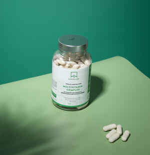 Bottle of Multivitamin Complex with capsules on a green surface - Aavalabs