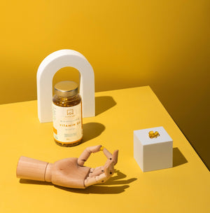 Bottle of Vitamin D3 1000 IU on a yellow background with a wooden hand holding a softgel - AAVALABS
